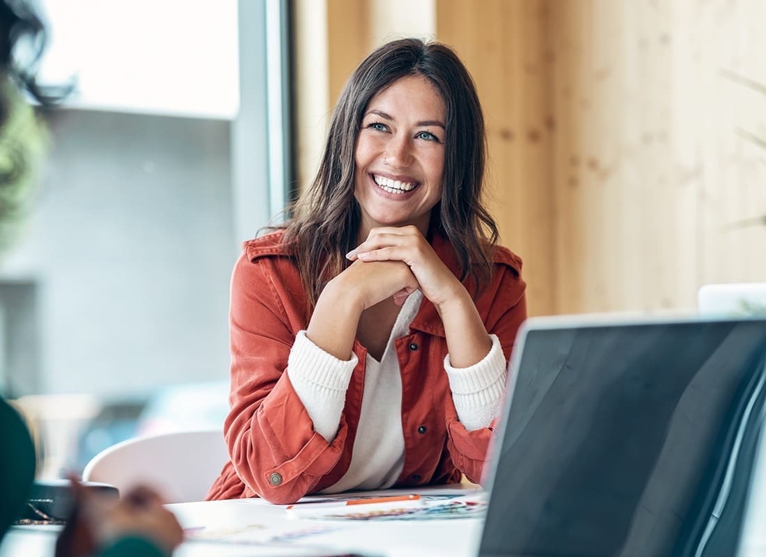 Employee Benefits - Closeup Portrait of a Cheerful Young Business Woman Sitting at a Table During a Meeting in the Office