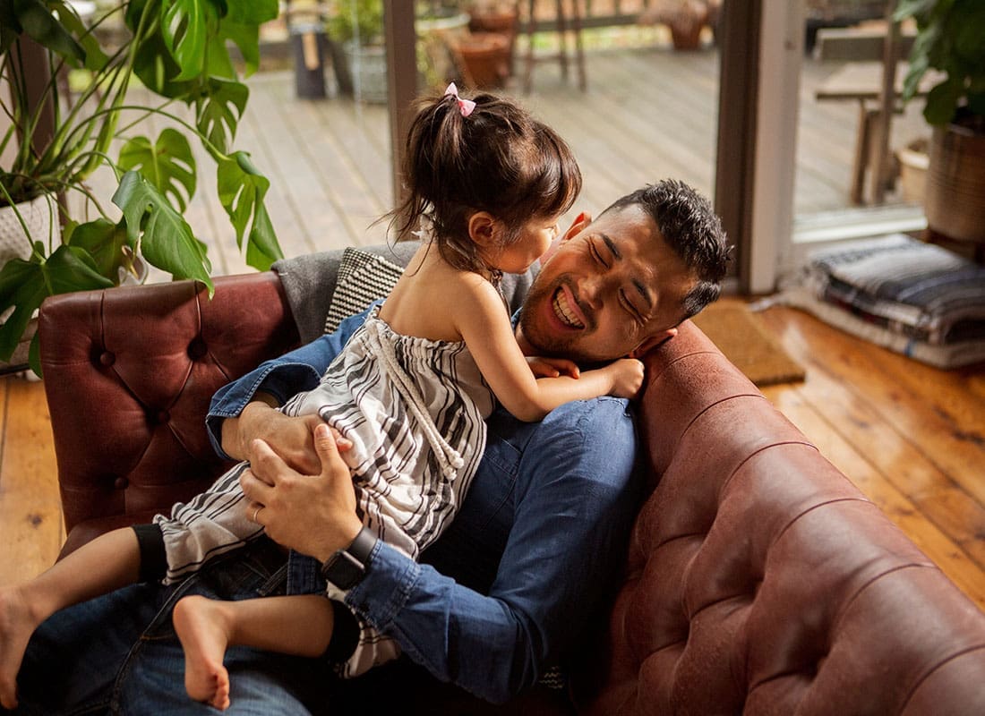 We Are Independent - Portrait of a Cheerful Father Having Fun Playing with his Young Daughter on the Sofa at Home