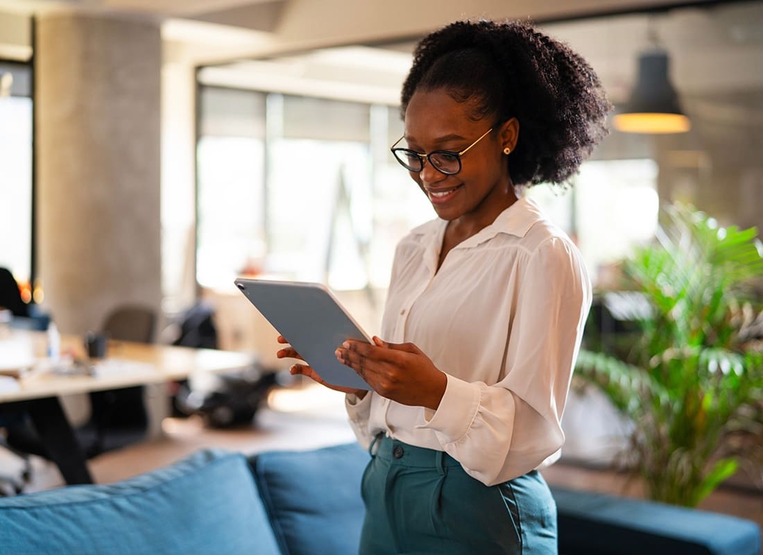 Blog - Portrait of a Smiling Young African American Business Woman Using a Tablet While Standing in the Office